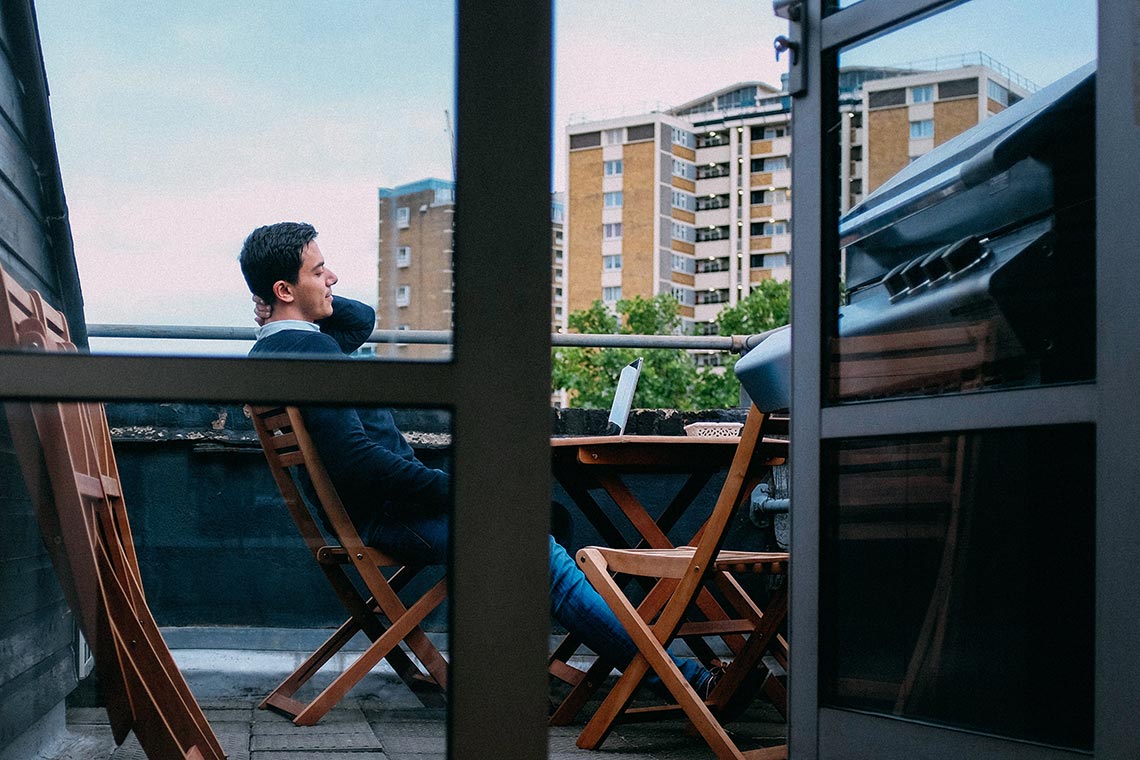 Ein Mann sitzt auf einem Balkon und entspannt